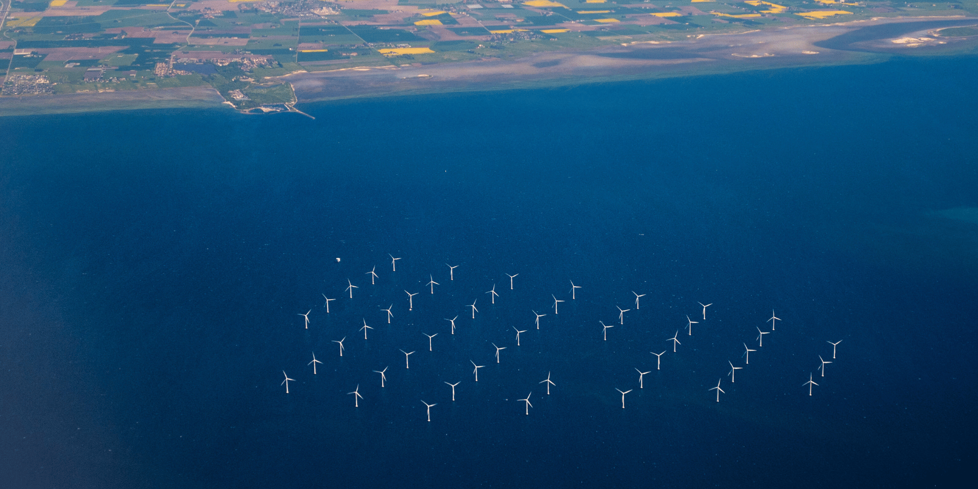 Eine Solaranlage im Meer vor einer Küste, aufgenommen aus der Luft