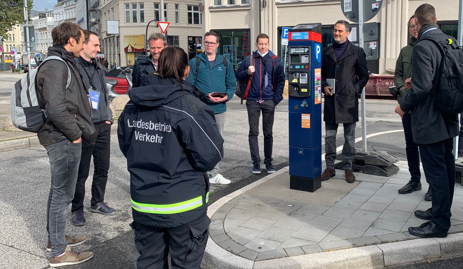group of people standing around the parking ticket machine