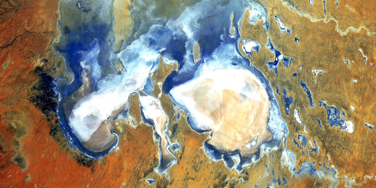Satellitenaufnahme einer Landschaft mit Wasser und roten Gesteinsformationen